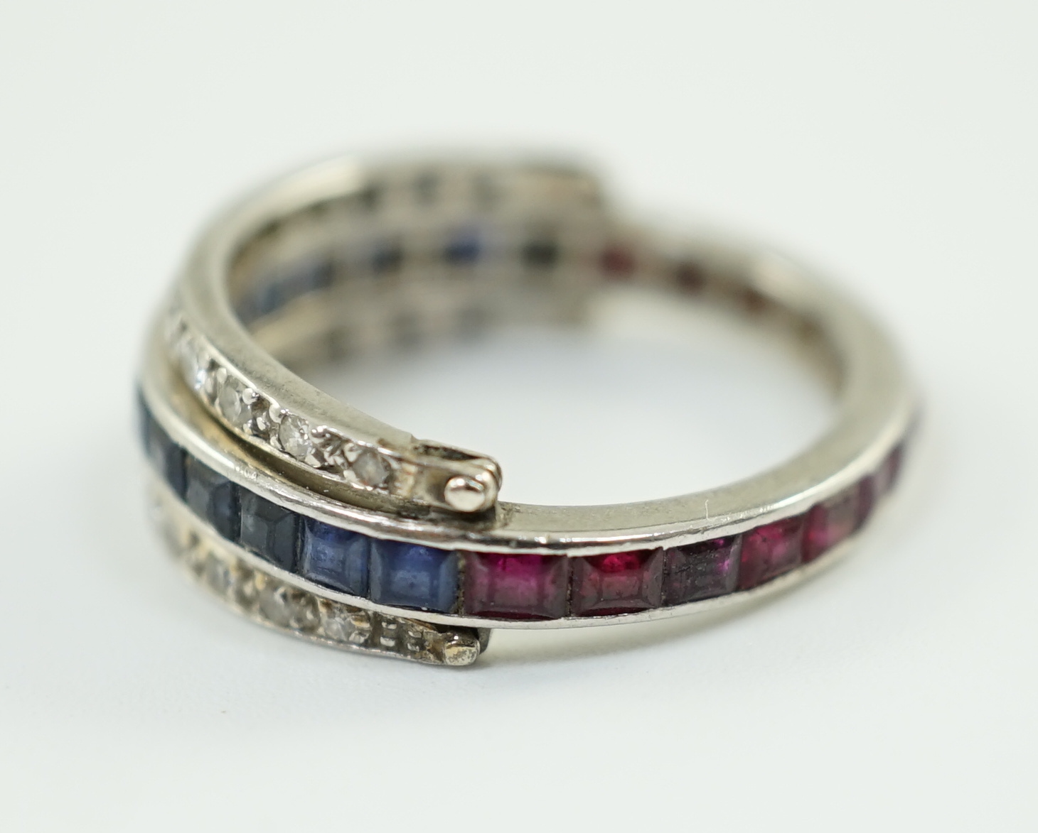 A mid 20th century white gold, diamond, ruby and sapphire set swivelling triple band eternity ring
